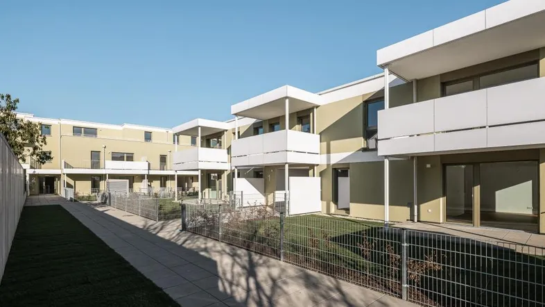 Moderne Reihenhäuser mit privaten Gärten und Terrassen in einer Wohnanlage.