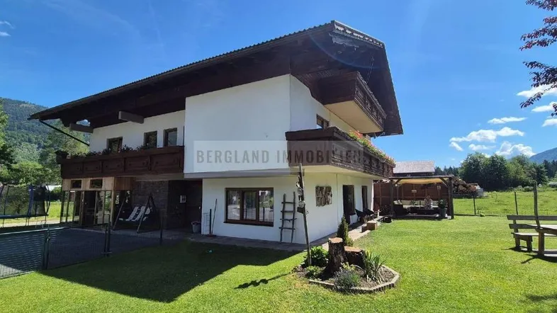 Ein charmantes Haus mit traditioneller Architektur, umgeben von einem gepflegten Garten und Bergblick.