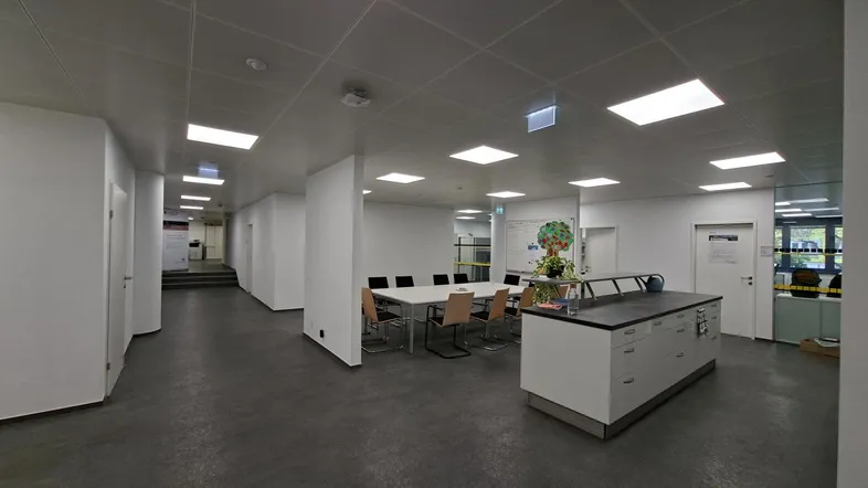 Geräumiger, moderner Bürobereich mit Besprechungstisch, Theke und hellem Flur.