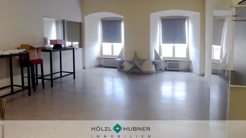 Geräumiger, heller Raum mit zwei Fenstern und hellem Laminatboden, ideal für Wohnzwecke.