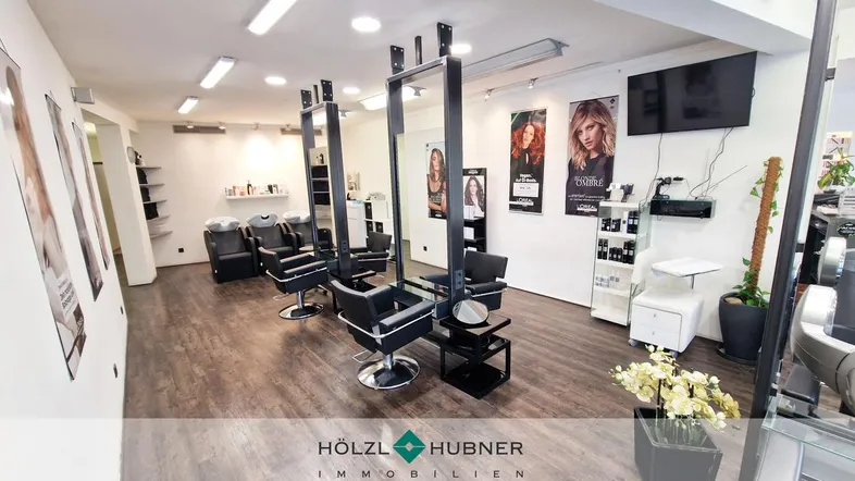 Geräumiger Friseursalon mit mehreren Bedienplätzen, dunklem Holzboden und moderner Einrichtung.
