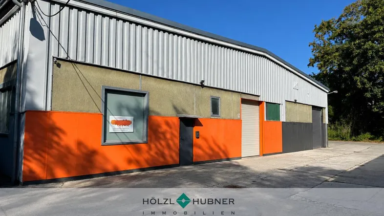 Außenansicht eines Industriegebäudes mit orangefarbenen Akzenten und Wellblechfassade unter blauem Himmel.