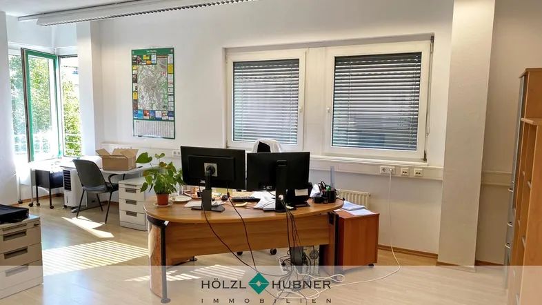 Geräumiges Büro mit mehreren Arbeitsplätzen, großen Fenstern und hellem Holzboden, ideal für ein Team.