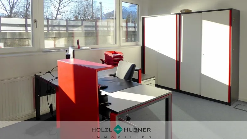 Helles Büro mit modernen roten Akzenten, Schränken und Blick ins Freie.