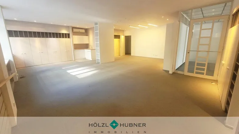 Geräumiger Büroraum mit Teppichboden, Einbauschränken und viel natürlichem Licht.