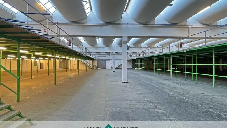 Geräumige Industriehalle mit hohen Decken, Oberlichtern und Belüftungssystemen, ideal für Lagerung oder Produktion.