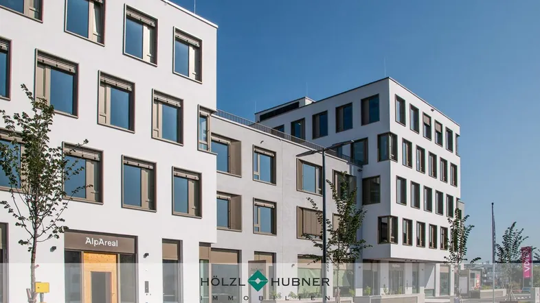 Moderne Bürogebäude mit weißer Fassade und vielen Fenstern unter blauem Himmel an einem sonnigen Tag.