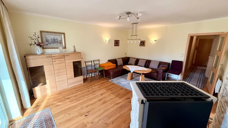 Gemütliches Wohnzimmer mit Holzboden, Ecksofa und einem modernen Kaminofen für behagliche Wärme.