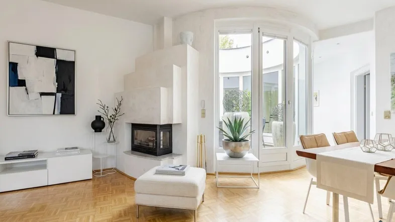 Heller Wohn- und Essbereich mit modernem Kamin, Parkettboden und Zugang zu einem Außenbereich.