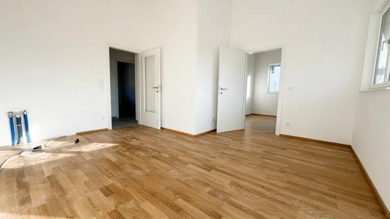 Helles, unmöbliertes Zimmer mit Parkettboden und mehreren Türen, bereit für die individuelle Gestaltung.