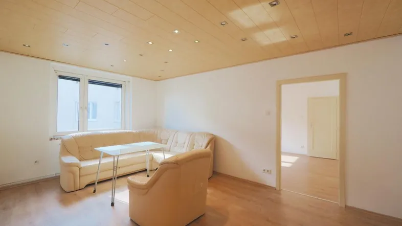 Helles Wohnzimmer mit Holzdeckenpaneelen, Einbaustrahlern und gemütlicher Sitzecke.