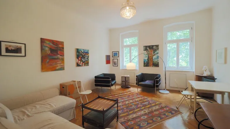 Helles Wohnzimmer mit Parkettboden, bequemen Sitzgelegenheiten und einem Essbereich am Fenster.