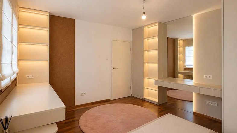Modernes Schlafzimmer mit Holzboden, integrierten Regalen und einem Schminktisch mit Spiegel.