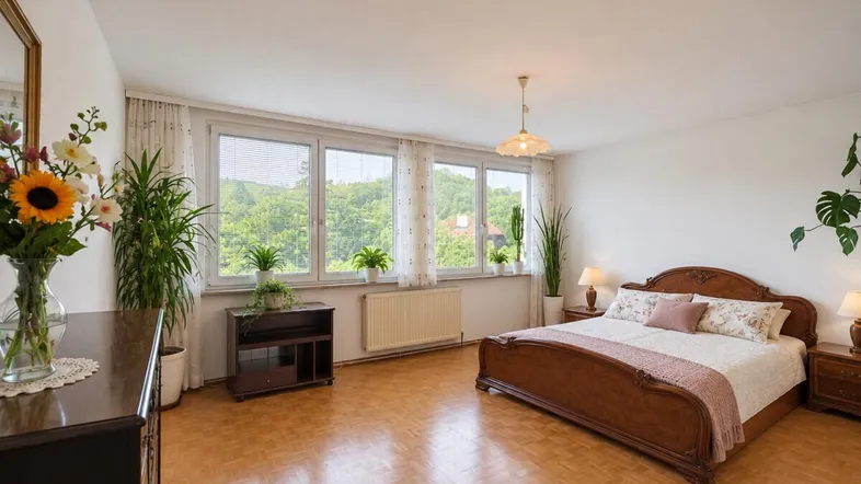 Helles Schlafzimmer mit klassischem Holzdoppelbett, Parkettboden und weitem Blick ins Grüne.