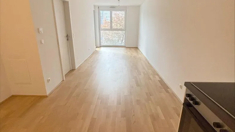 Heller Wohnbereich mit neuem Parkettboden und großen Fenstern, die viel Tageslicht hereinlassen.
