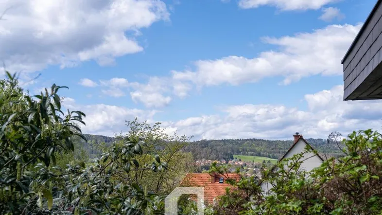 Panoramablick über grüne Hügel und Dächer von Häusern unter blauem Himmel.