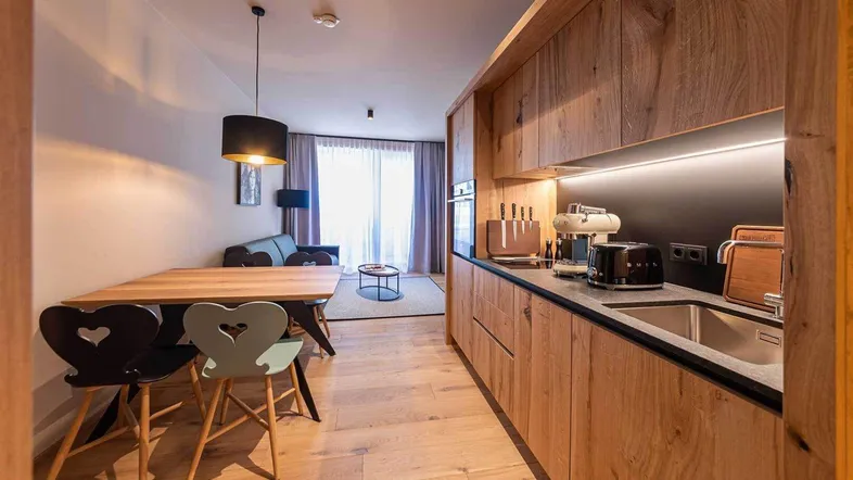 Moderne offene Küche mit Essbereich und angrenzendem Wohnzimmer, ausgestattet mit Holzelementen und Parkettboden.