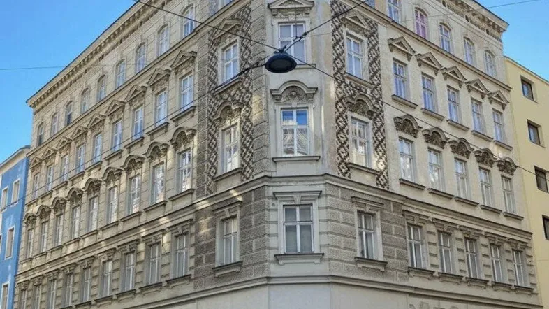 Historisches Eckgebäude mit klassischer Architektur und vielen Fenstern in städtischer Umgebung.