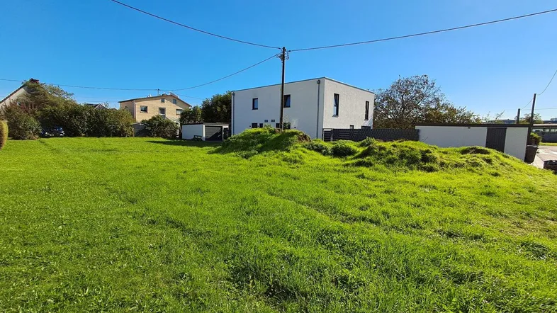 Weitläufige grüne Fläche eines Grundstücks mit modernen Wohnhäusern im Hintergrund.