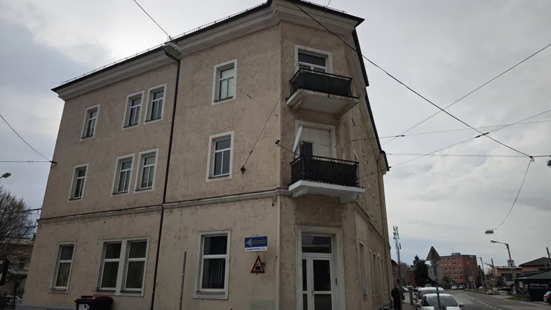 Eckgebäude mit mehreren Etagen und Balkonen an einer städtischen Straße.
