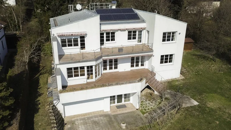 Luftaufnahme des modernen weißen Gebäudes mit mehreren Balkonen und Solarpaneelen auf dem Dach.