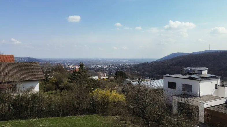 Weitläufiger Blick über die Landschaft und eine Stadt in der Ferne unter blauem Himmel.