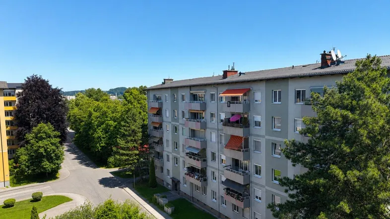 Panoramablick auf Wohngebäude, Straßen und üppige grüne Bäume unter blauem Himmel.