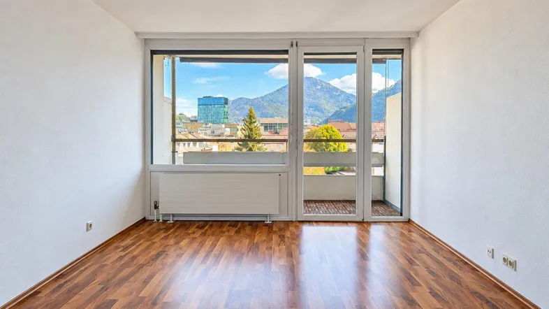 Helles Zimmer mit Holzboden und Zugang zum Balkon, bietet einen weiten Blick auf die Berge.