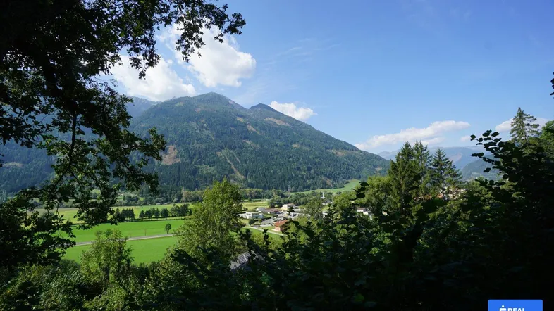 Panoramablick auf die umliegende Berglandschaft und ein idyllisches Tal mit einem kleinen Dorf.