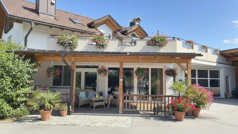 Überdachte Terrasse mit gemütlichen Korbmöbeln und Blumenkästen am traditionellen Haus.
