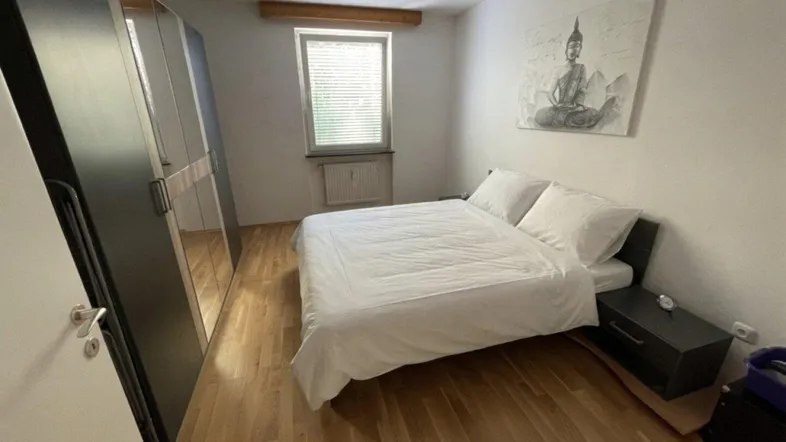 Helles Schlafzimmer mit Holzboden, großem Spiegelschrank und Fenster für natürliches Licht.