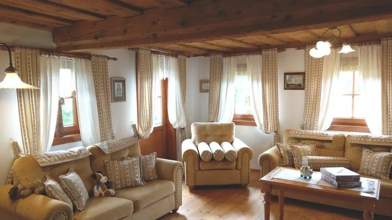 Gemütliches Wohnzimmer im Landhausstil mit Holzbalkendecke, Parkettboden und bequemen Sofas.