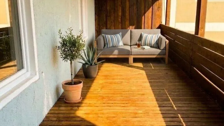 Sonniger Balkon mit Holzfußboden und bequemen Outdoor-Möbeln, ideal zum Entspannen im Freien.