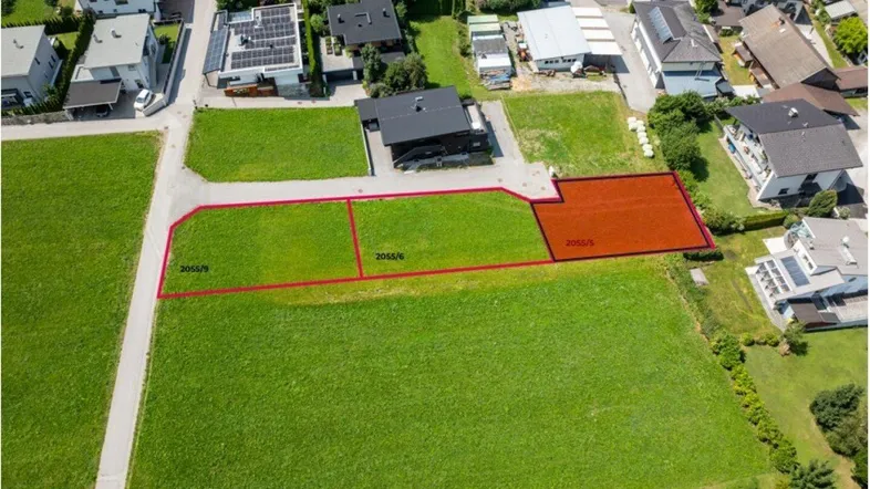 Luftaufnahme von Baugrundstücken mit umliegenden Häusern und grünen Feldern in ländlicher Umgebung.