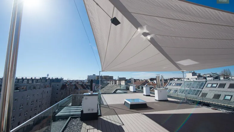 Große Dachterrasse mit Sonnensegel und weitem Blick über die Stadt.
