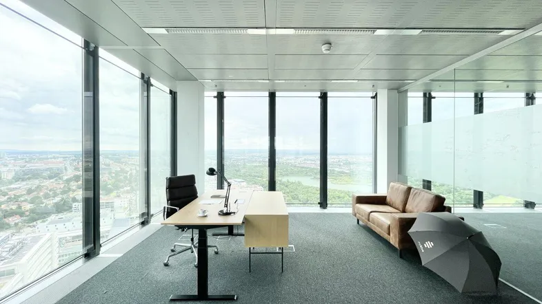 Modernes Büro mit Teppichboden, raumhohen Fenstern und Panoramablick auf die Stadt.