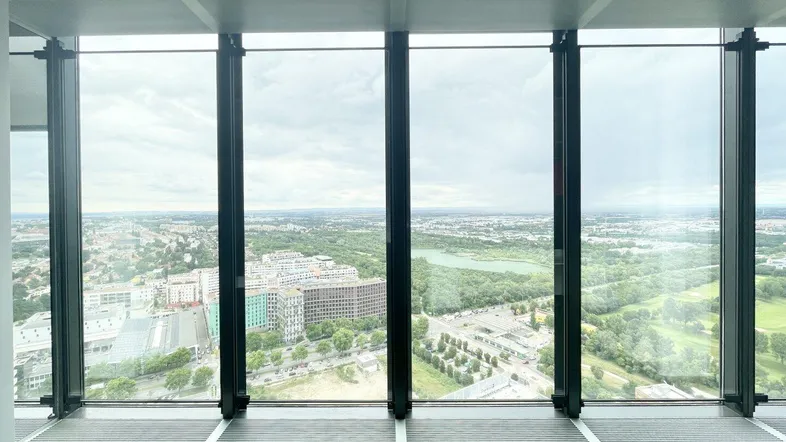 Geräumiger Büroraum mit großen Fenstern und weitem Blick über die Stadt und grüne Flächen.