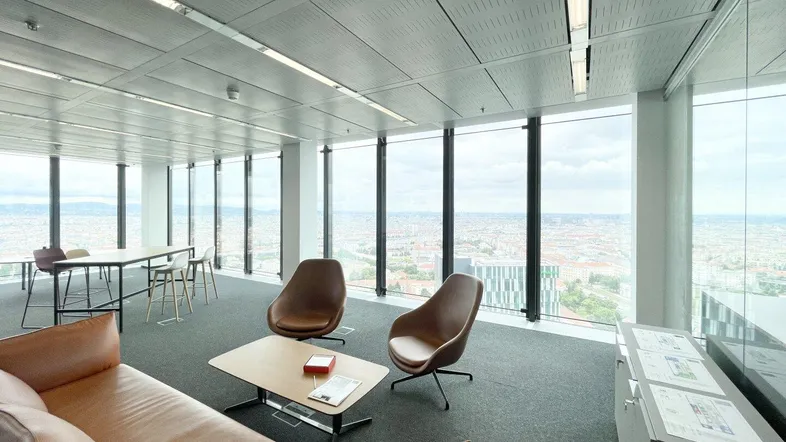 Moderner Bürobereich mit bequemen Ledersofas und Sesseln, bietet einen weiten Stadtblick durch große Fenster.