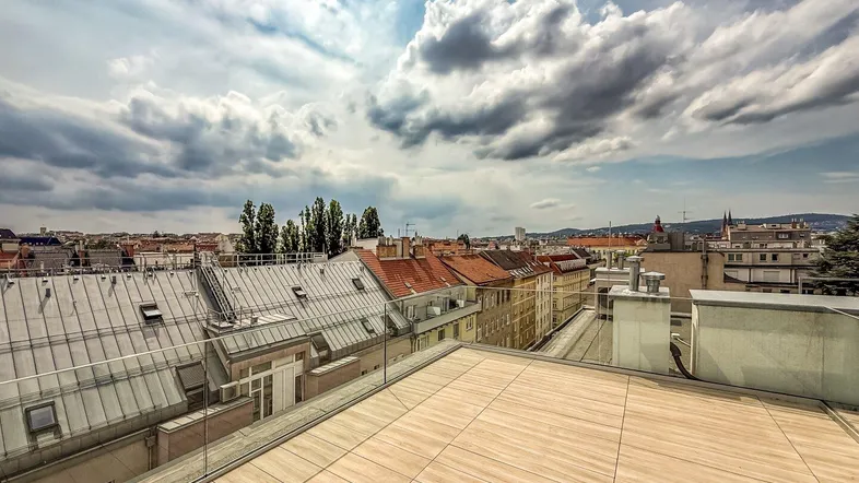 Geräumige Dachterrasse mit Fliesenboden und weitem Blick über die Stadt und die umliegenden Dächer.