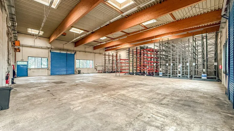 Große, leere Lagerhalle mit hohen Decken, Betonboden und sichtbaren Holzträgern, bereit zur Nutzung.