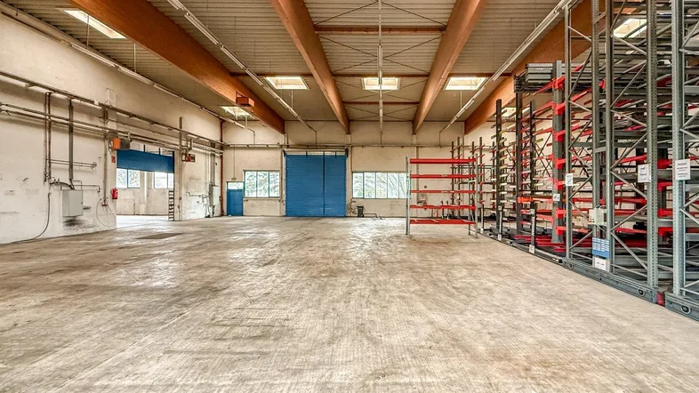 Geräumige Lagerhalle mit hoher Decke, Betonboden und Regalsystemen, bereit zur Nutzung.