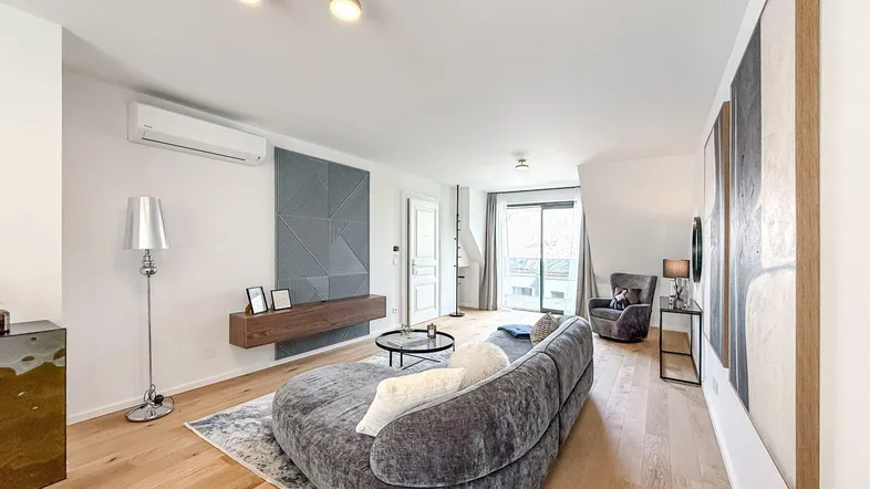 Helles Wohnzimmer mit modernem Sofa, Holzboden und Zugang zu einem Balkon.