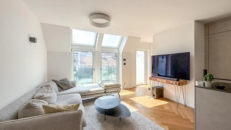 Helles Wohnzimmer mit modernem Sofa, Holzboden und großen Dachfenstern für viel Tageslicht.