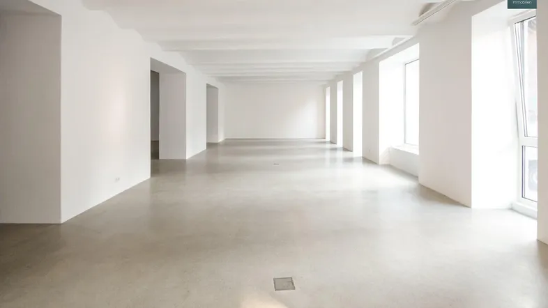 Großer, heller Büroraum mit hohen Decken und poliertem Betonboden, bereit zur individuellen Gestaltung.