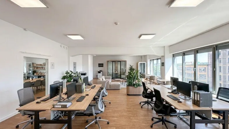 Geräumiger, modern eingerichteter Großraumbüro mit vielen Arbeitsplätzen und großen Fenstern für viel Tageslicht.