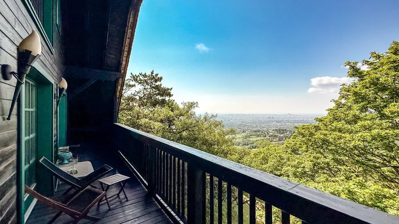 Geräumiger Balkon mit Holzboden und atemberaubendem Weitblick über die Landschaft und Stadt.
