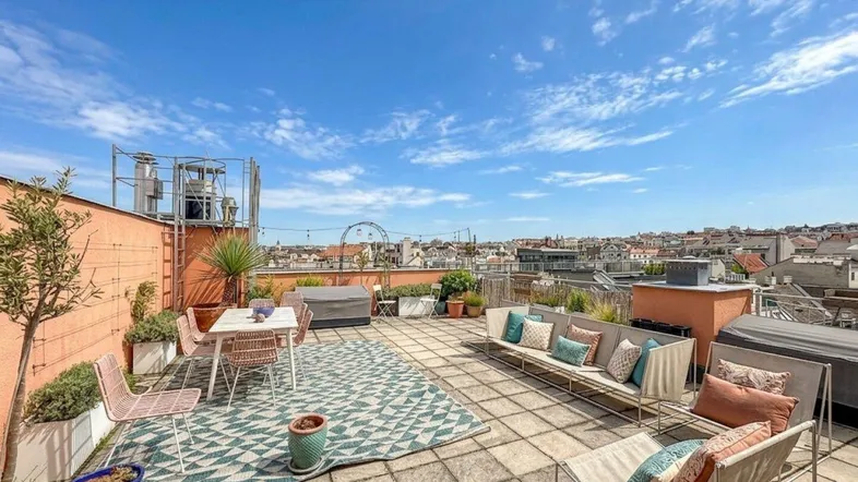 Große Dachterrasse mit Sitzgelegenheiten, Pflanzen und weitem Blick über die Stadt.