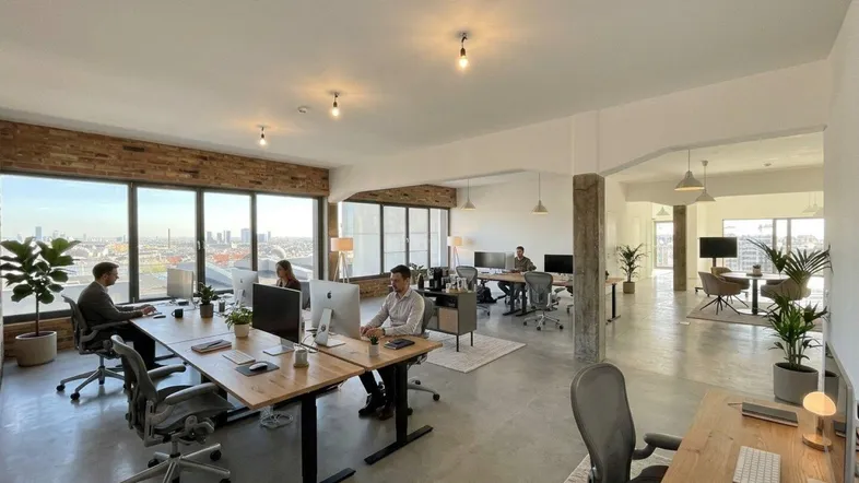 Großes, modernes Büro mit mehreren Arbeitsplätzen, Stadtblick und freiliegenden Ziegelwänden.