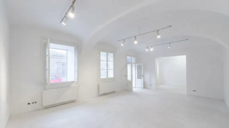 Heller, leerer Gewerberaum mit gewölbter Decke, großen Fenstern und moderner Beleuchtung.