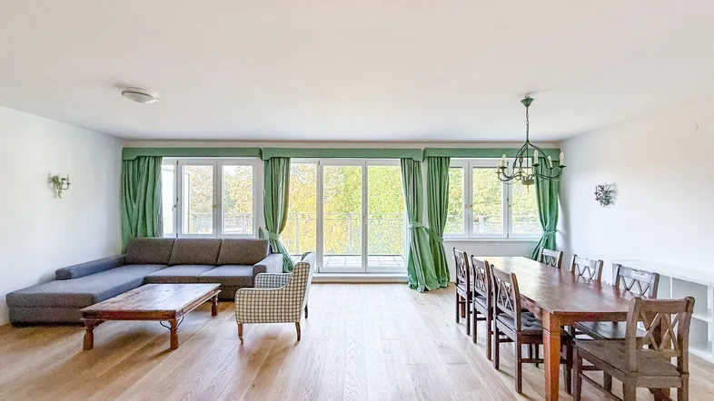 Geräumiger Wohn-Essbereich mit hellem Parkettboden, großen Fenstern und Zugang zum Balkon.